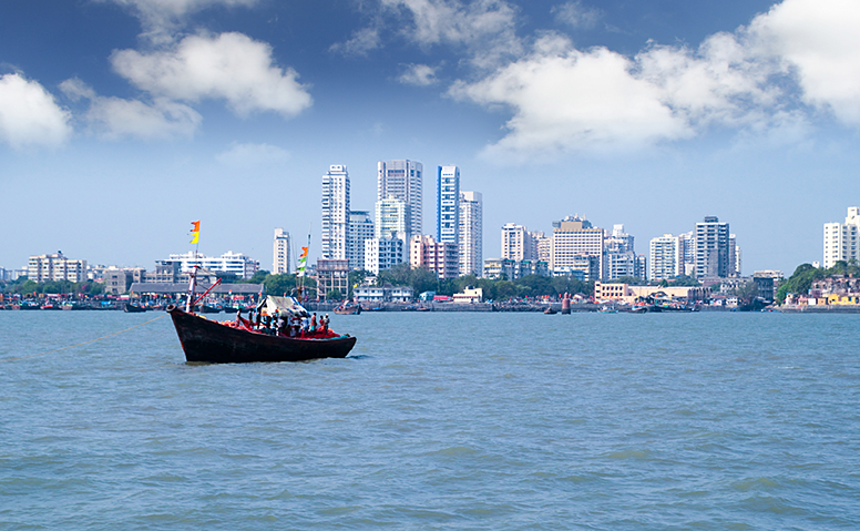 India: Skyline of Mumbai, in the foreground a moving colourful ship India: Skyline of Mumbai, in the foreground a moving colourful ship