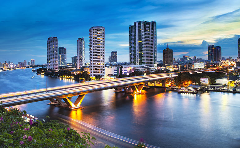 Thailand: Photo of a bridge over the Chao Phraya river in Bangkok, the bridge is illuminated and there are houses and skyscrapers in the background Thailand: Photo of a bridge over the Chao Phraya river in Bangkok, the bridge is illuminated and there are houses and skyscrapers in the background